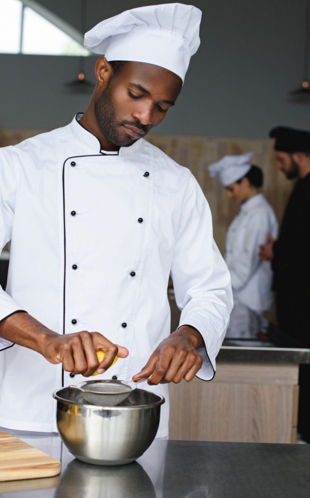 african american chef squeezing lemons at restaurant kitchen