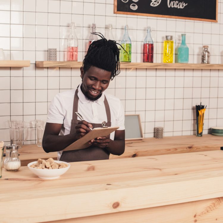 smiling african american barista taking order at bar counter